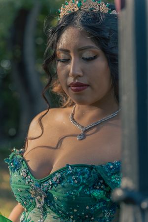 Close-up details of an emerald green gown with crystal embellishments and matching tiara.