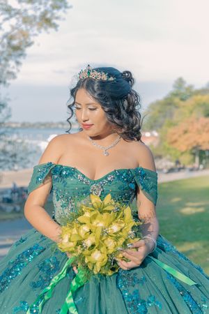 Emerald ballgown with beaded bodice and yellow orchid bouquet captured in outdoor setting.
