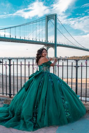 Majestic emerald ball gown photographed against bridge and waterfront backdrop.