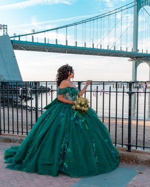 Dramatic emerald gown with voluminous skirt captured in series of outdoor photos by bridge.