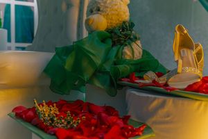 Event decor setup with emerald green fabrics and red floral arrangements on pedestals.