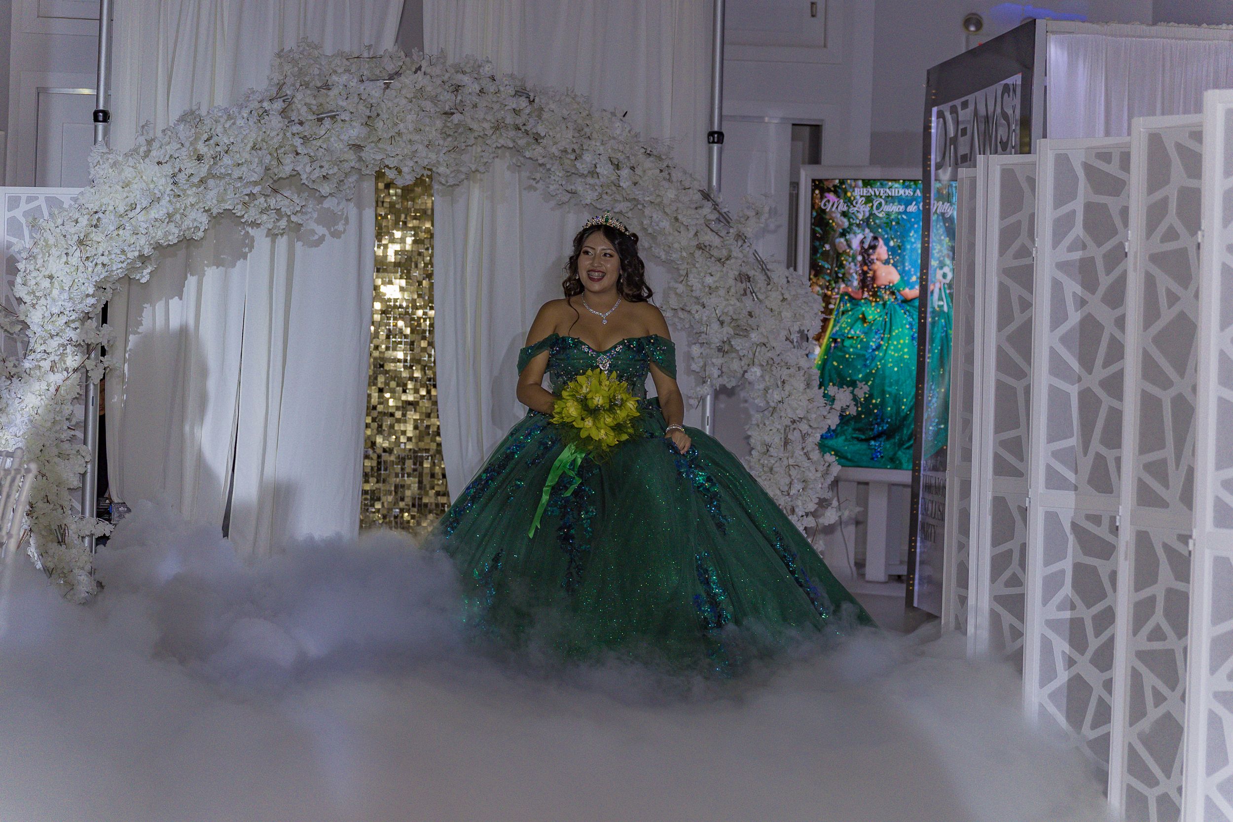 Elegant white event space decorated with floral arrangements and draped fabric.