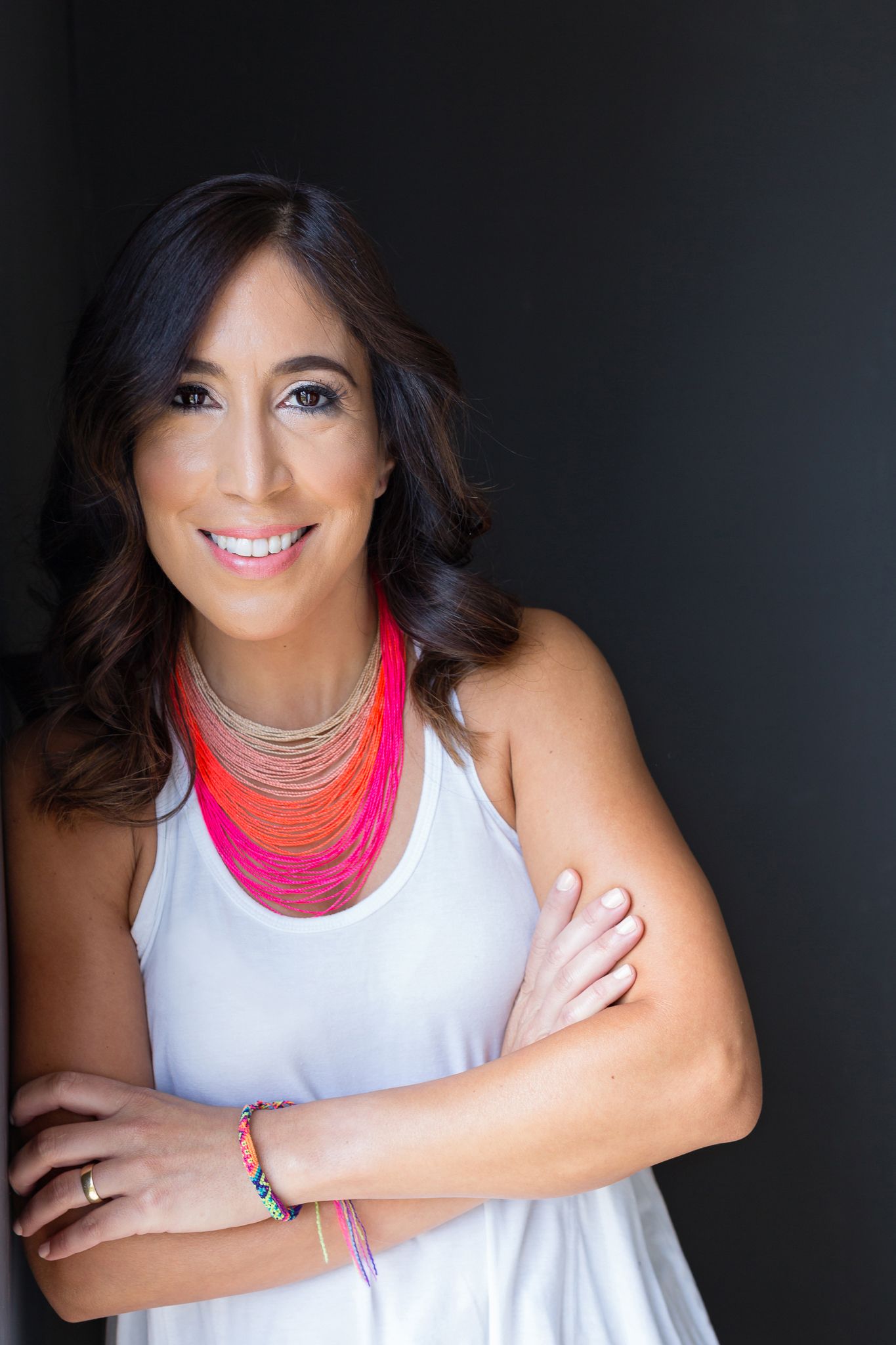 Studio portraits with black background and bright pink statement necklace.