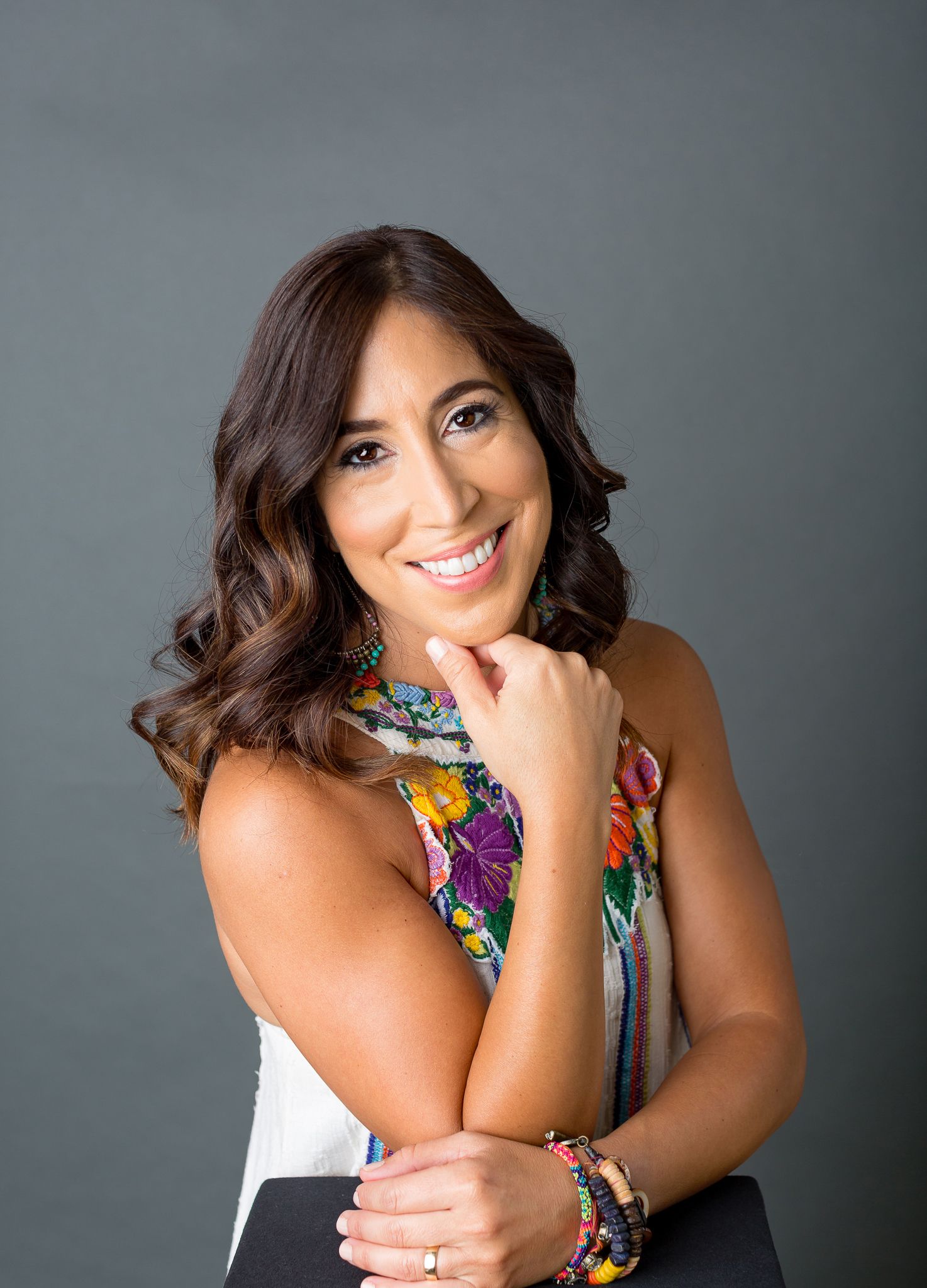 Studio portraits with dark background featuring colorful statement necklace.