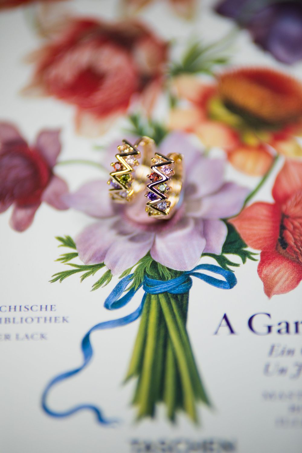 Gold ring with geometric design displayed on floral print with blue ribbon.