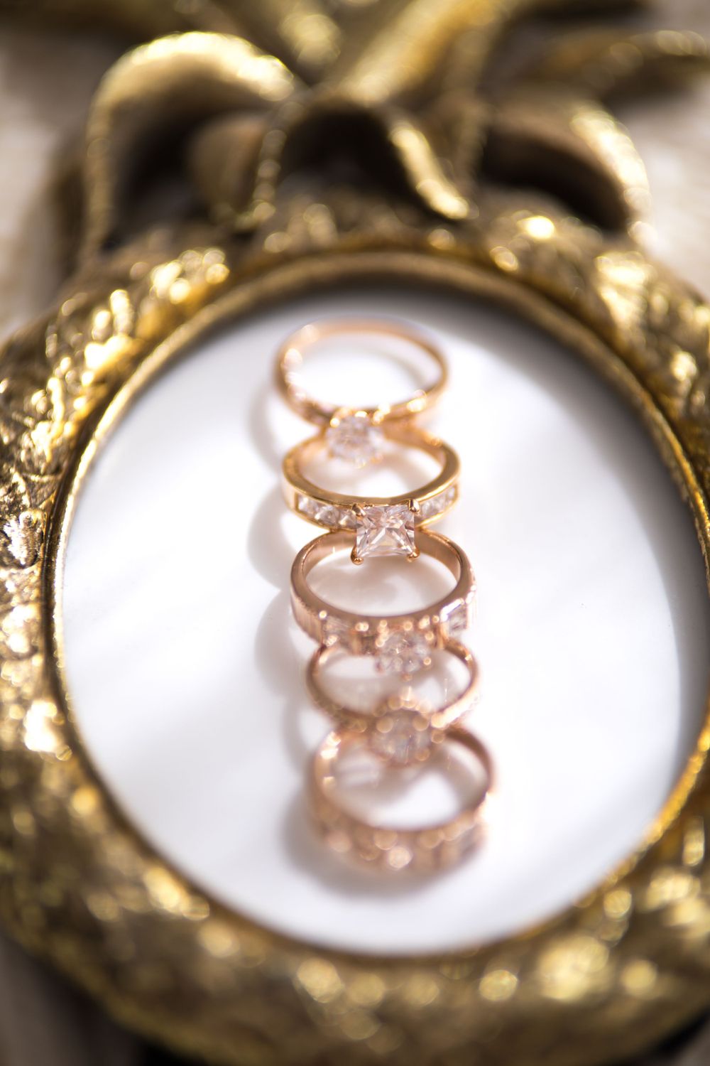 Rose gold engagement rings with diamonds displayed in vintage gold frame.