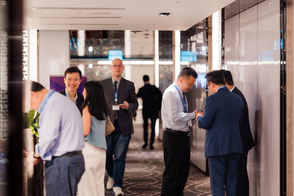 Business professionals gather in a modern office hallway for a corporate meeting or networking event.