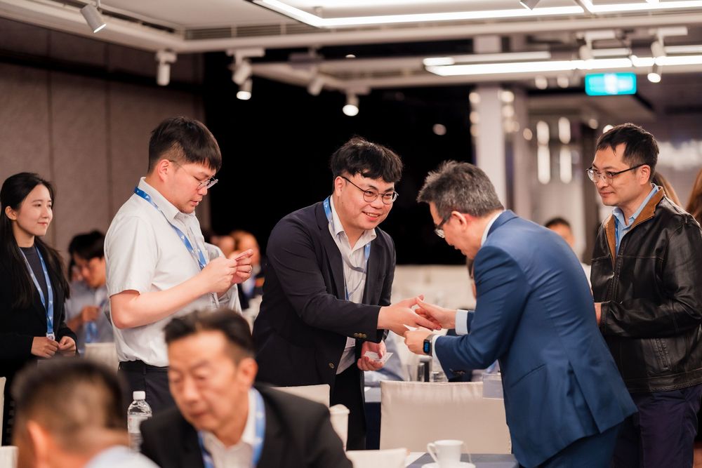 Business professionals gather around a table examining documents during a corporate meeting in a modern conference room.