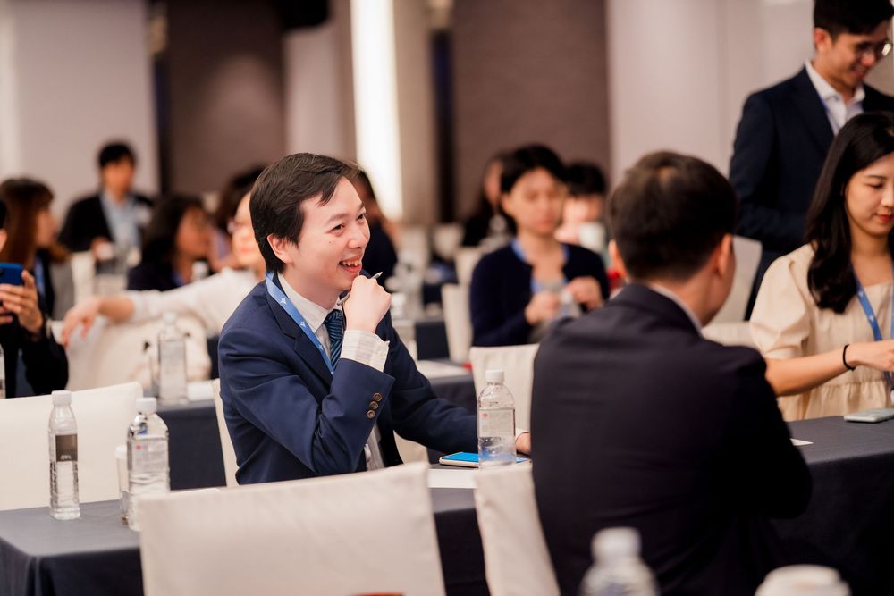Attendees engaged in animated discussion during a business conference in a well-lit meeting space.