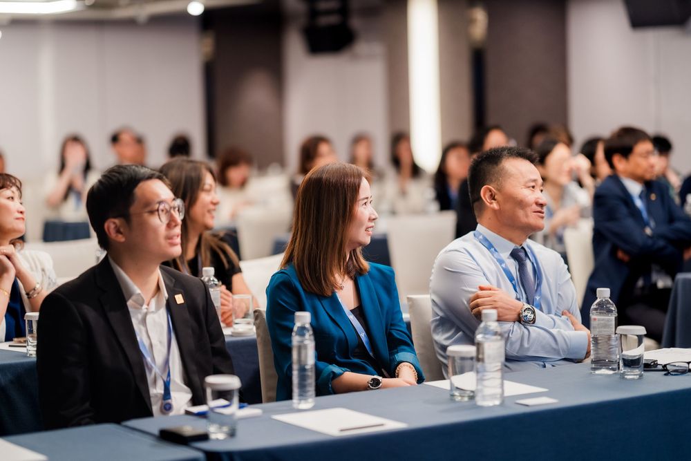 Business professionals seated at conference tables engage in discussion during a corporate meeting.
