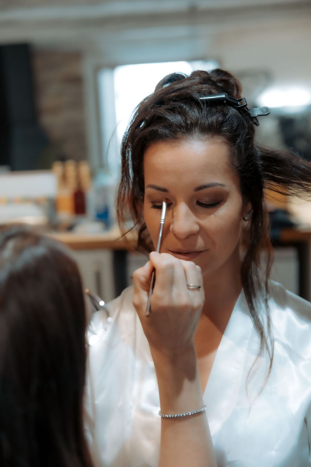 A person in a white top applies makeup in a sequence of close-up shots showing their beauty routine.