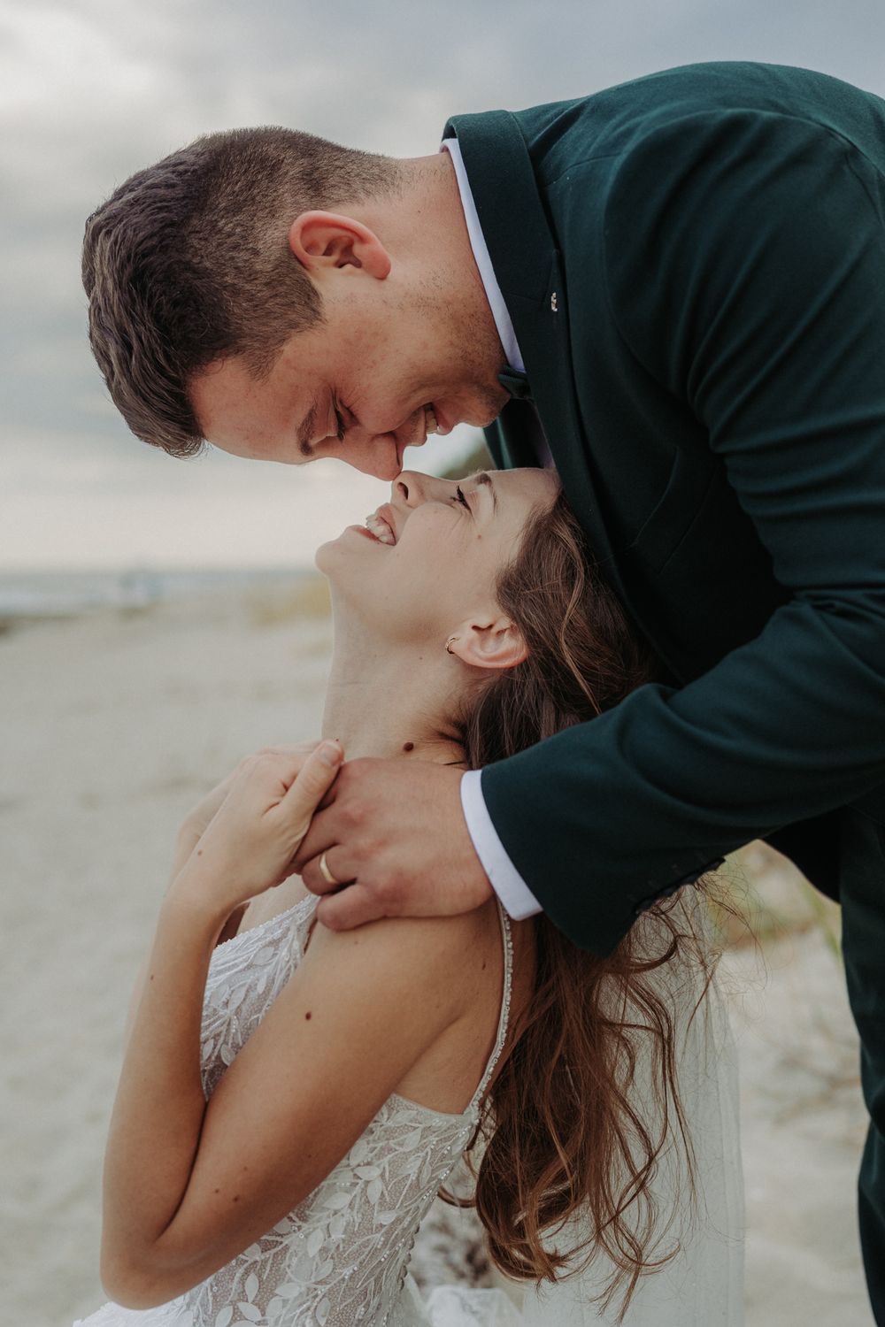 Romantic wedding couple shares intimate kisses in a sequence of tender moments on a cloudy day.