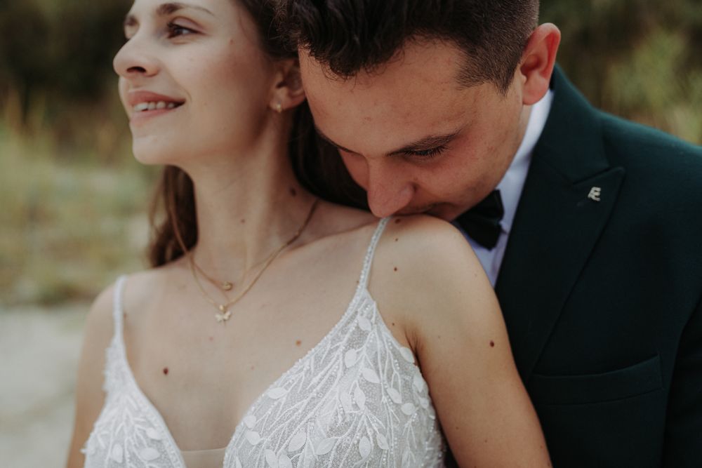 A romantic close-up moment between a couple in wedding attire with soft lighting and natural scenery.