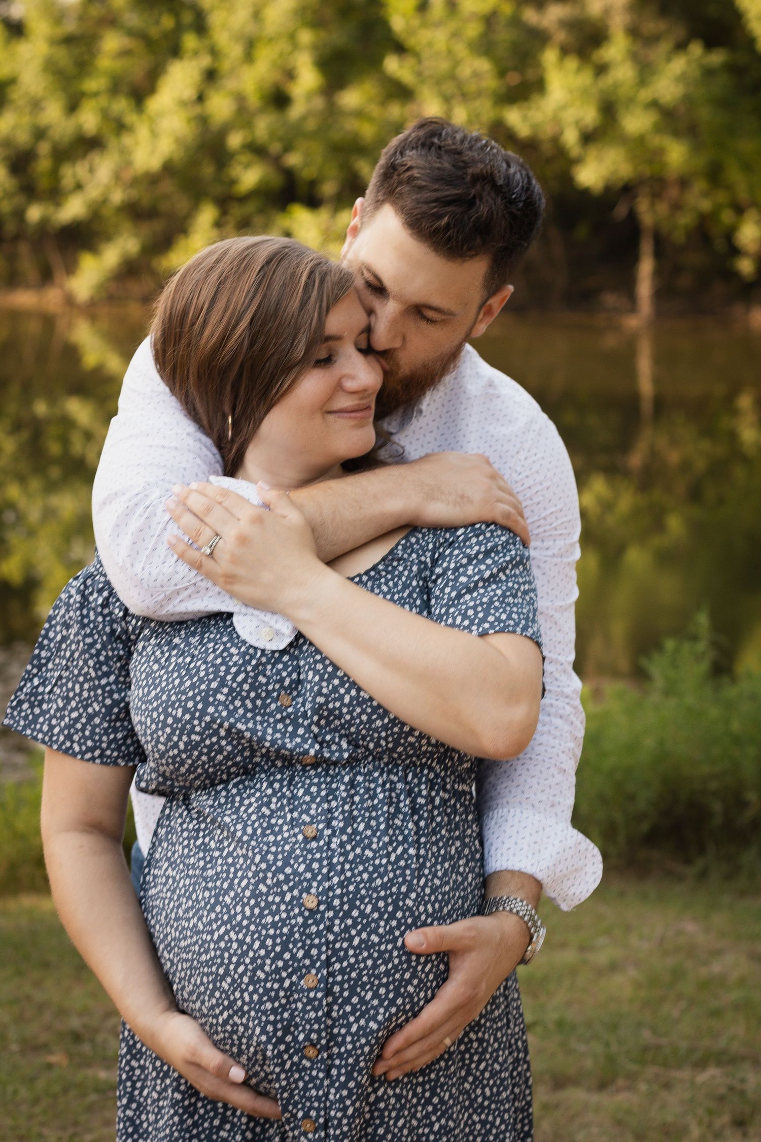Intimate maternity photos of a couple embracing outdoors with golden sunlight filtering through trees at Kickerillo Mischer Preserve.