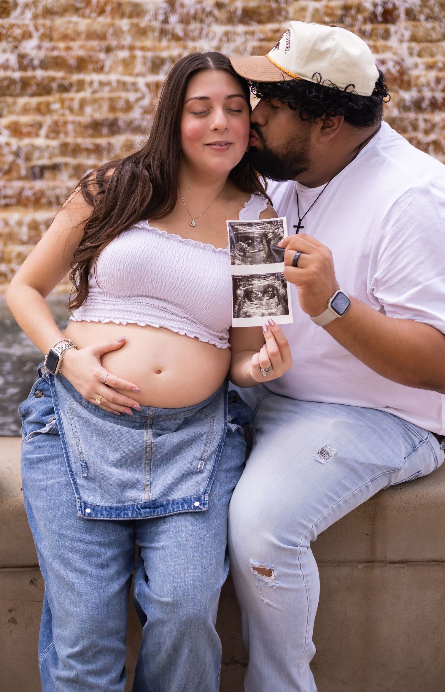 Couple in casual white and denim outfits sharing intimate pregnancy reveal moments by the water way in the Woodlands TX.