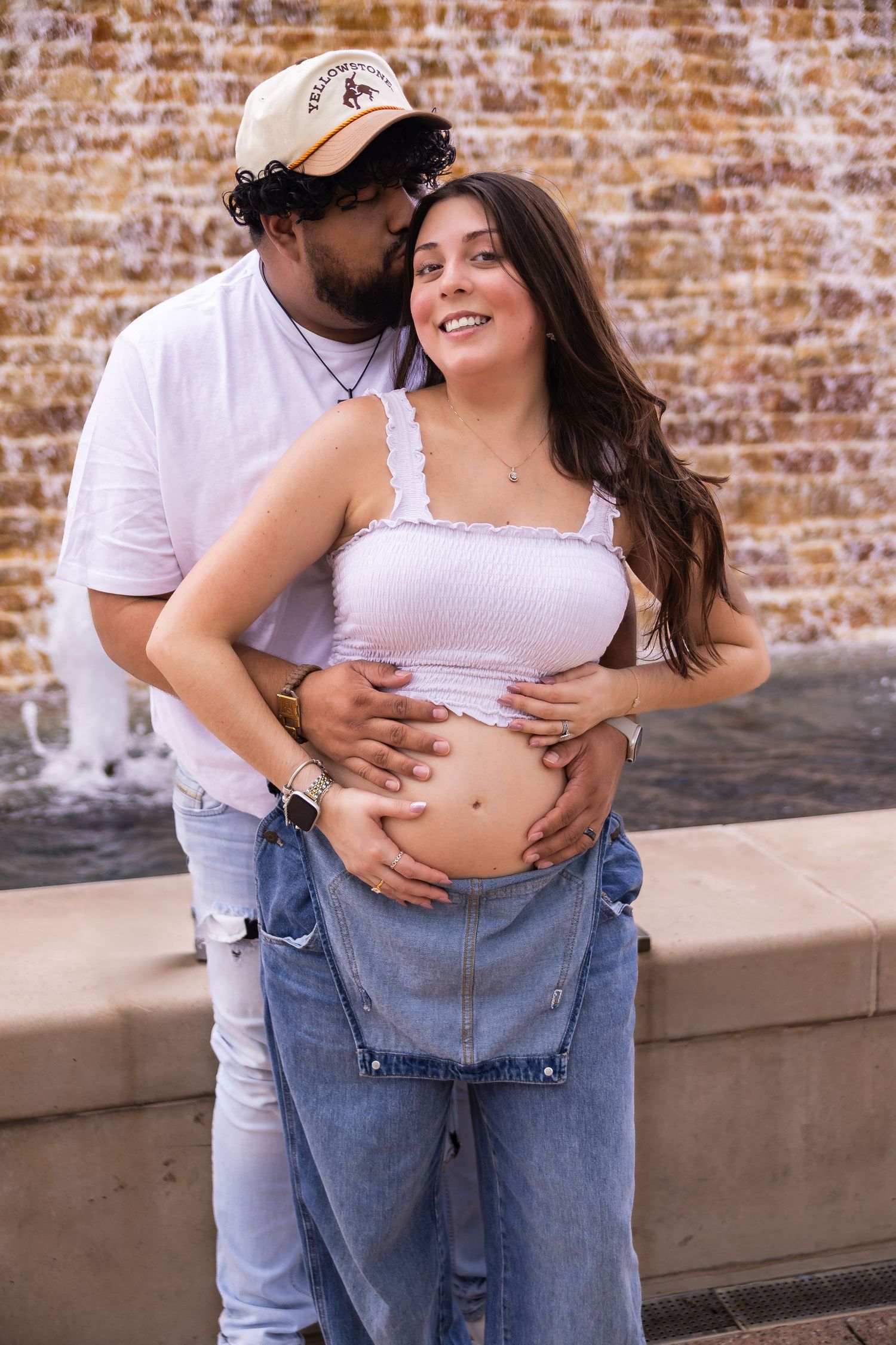 Maternity photo series against rustic brick wall showing casual pregnancy documentation, by the water way in the Woodlands TX.