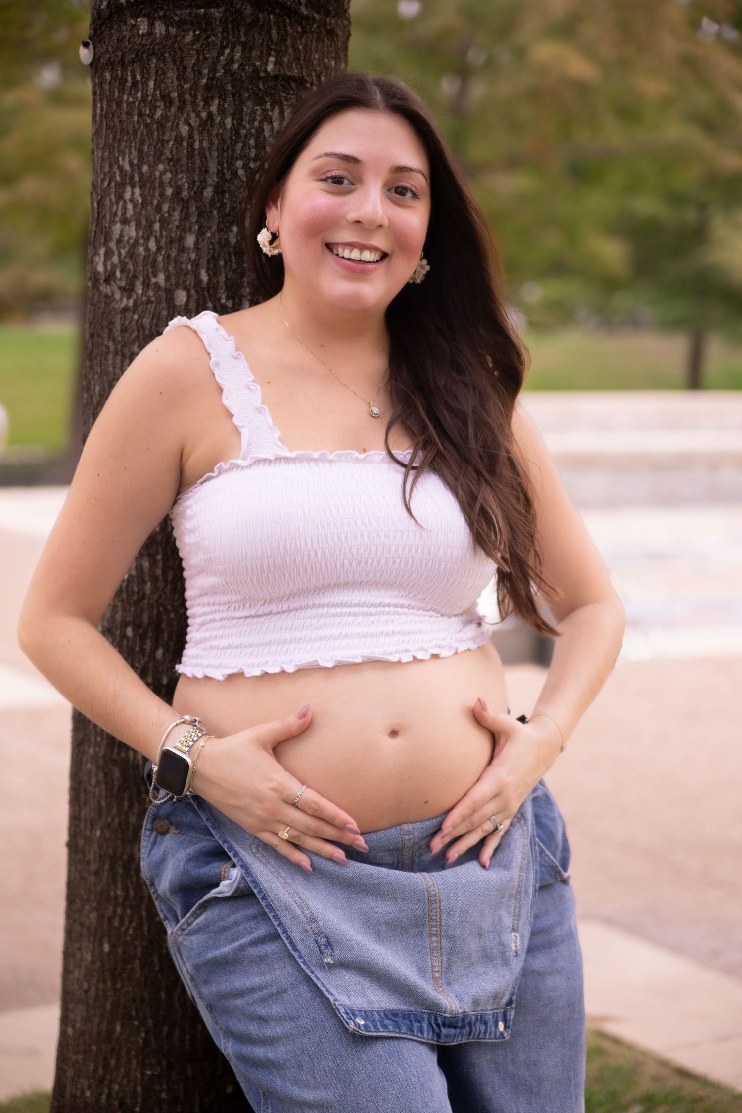 Solo maternity portraits outdoors showing bump progress in casual white top and jeans by the water way in the Woodlands TX.