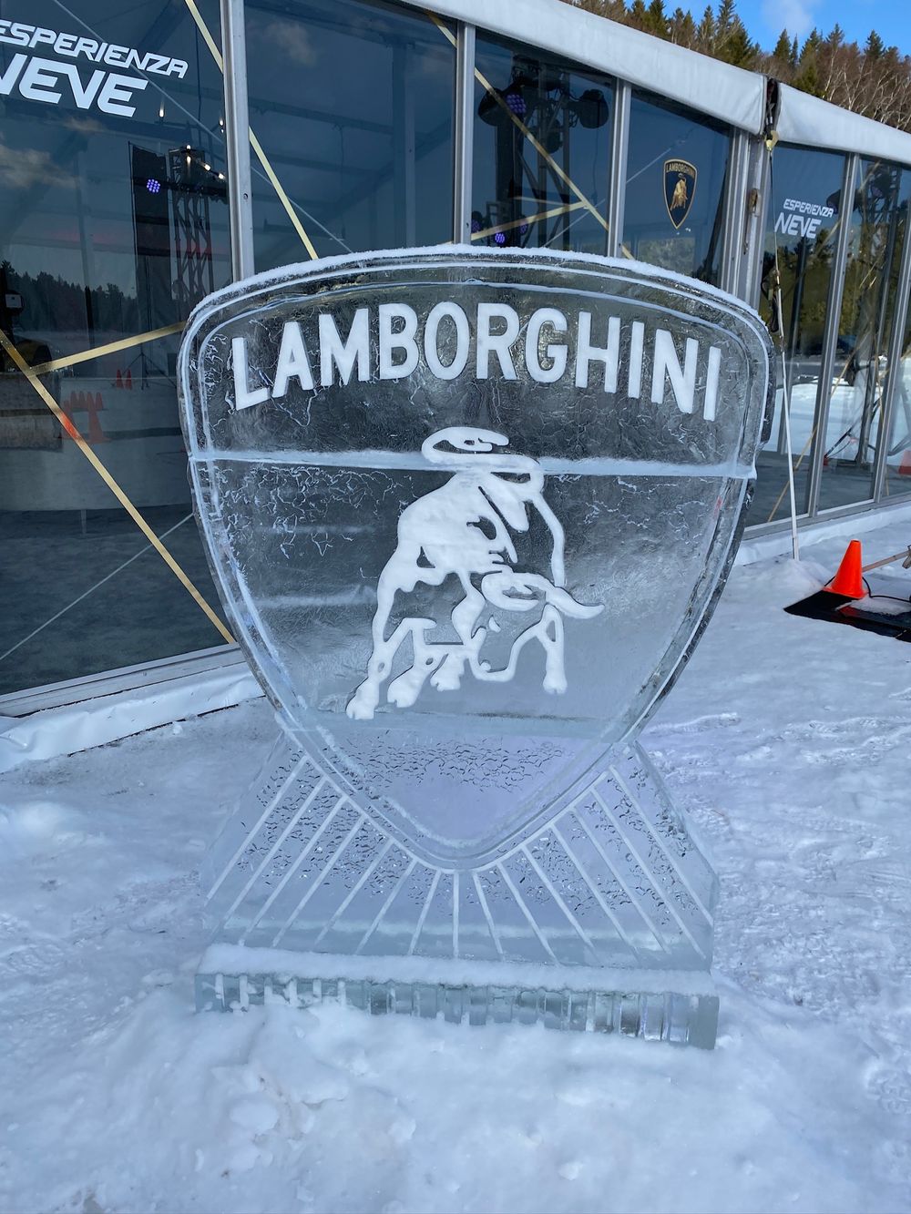 Ice sculpture displays featuring the Lamborghini logo and bull emblem carved in crystal-clear ice blocks at a winter event.