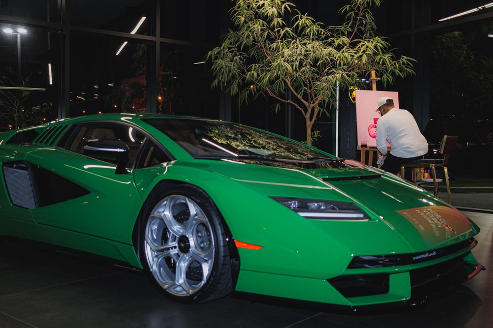 A bright green Lamborghini supercar photographed at night with chrome wheels and LED headlights illuminated.