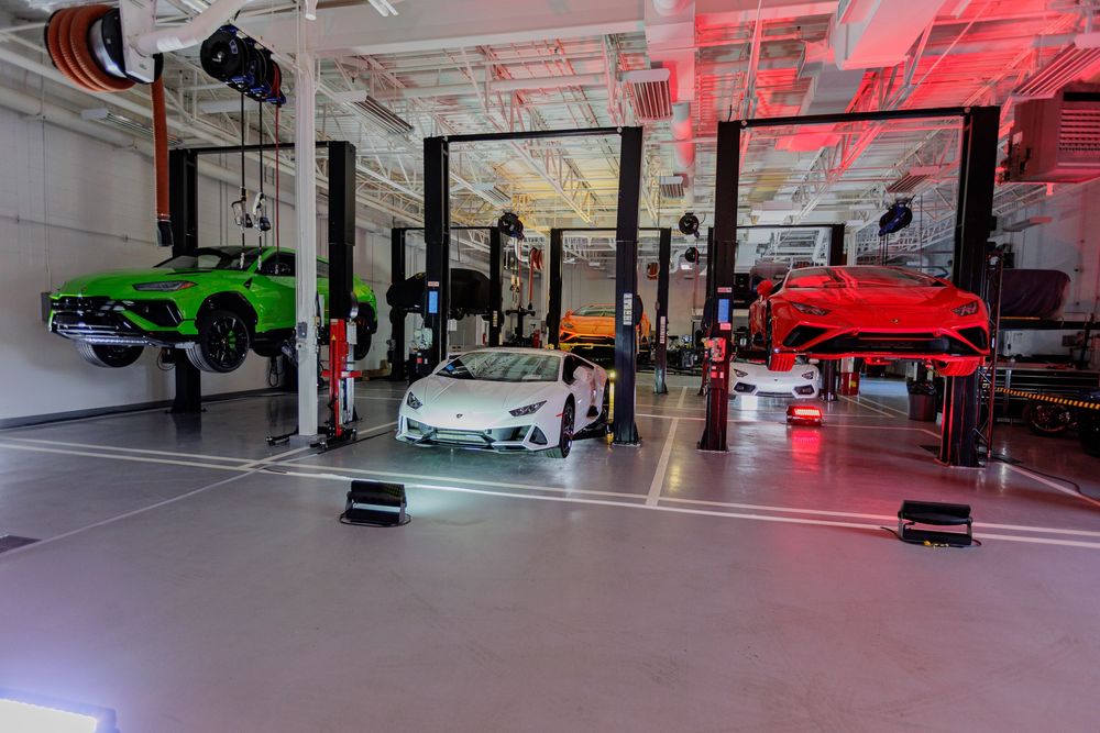 Modern car dealership showroom interior with sleek vehicles and dramatic red lighting effects on display.