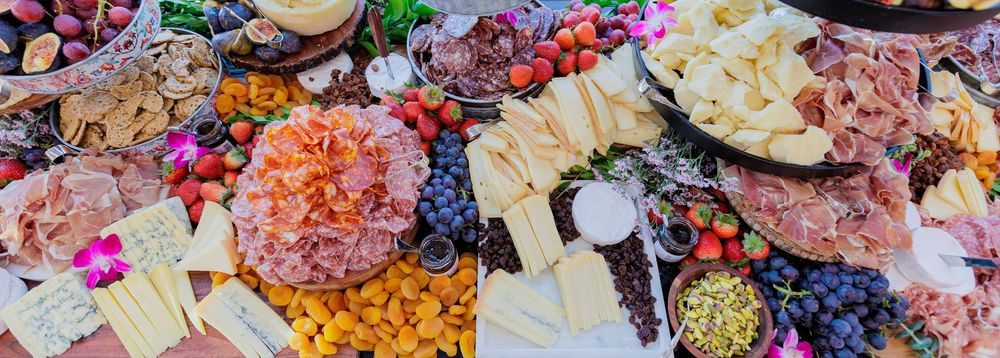 Colorful charcuterie board with assorted meats, cheeses, fruits, nuts and crackers arranged on a wooden surface.