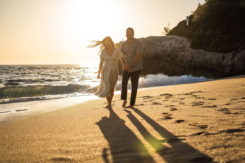 Silhouettes of people walking along a beach at sunset with golden light shining through.