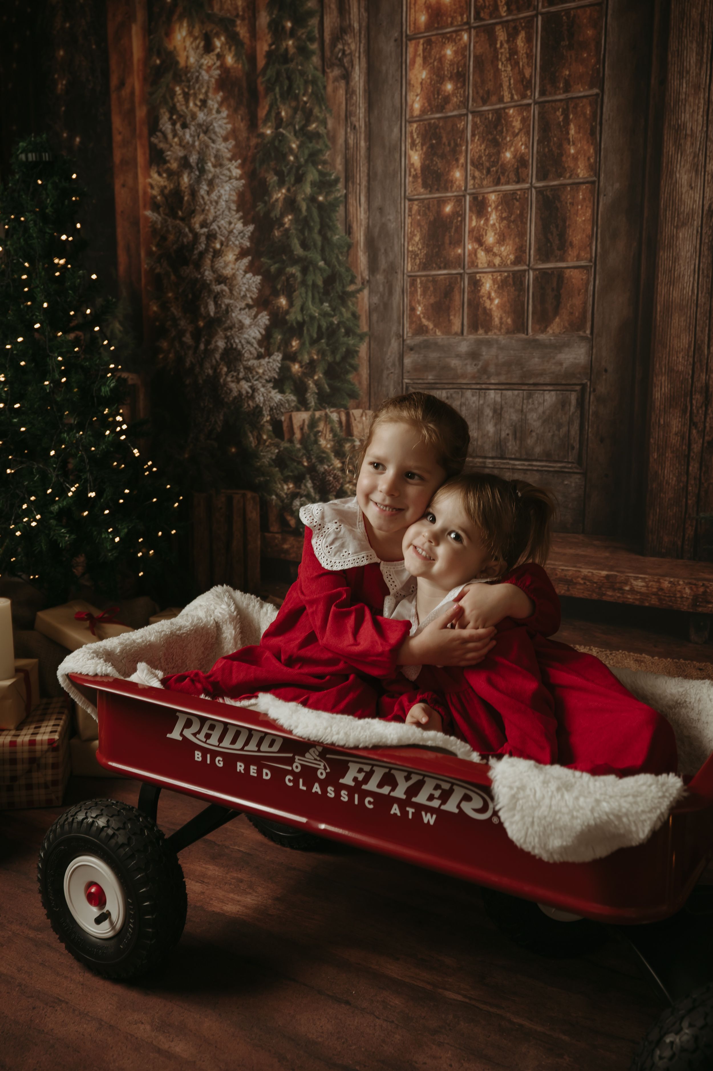 A series of holiday photos showing children lying in a vintage red Radio Flyer wagon against a rustic wooden backdrop.