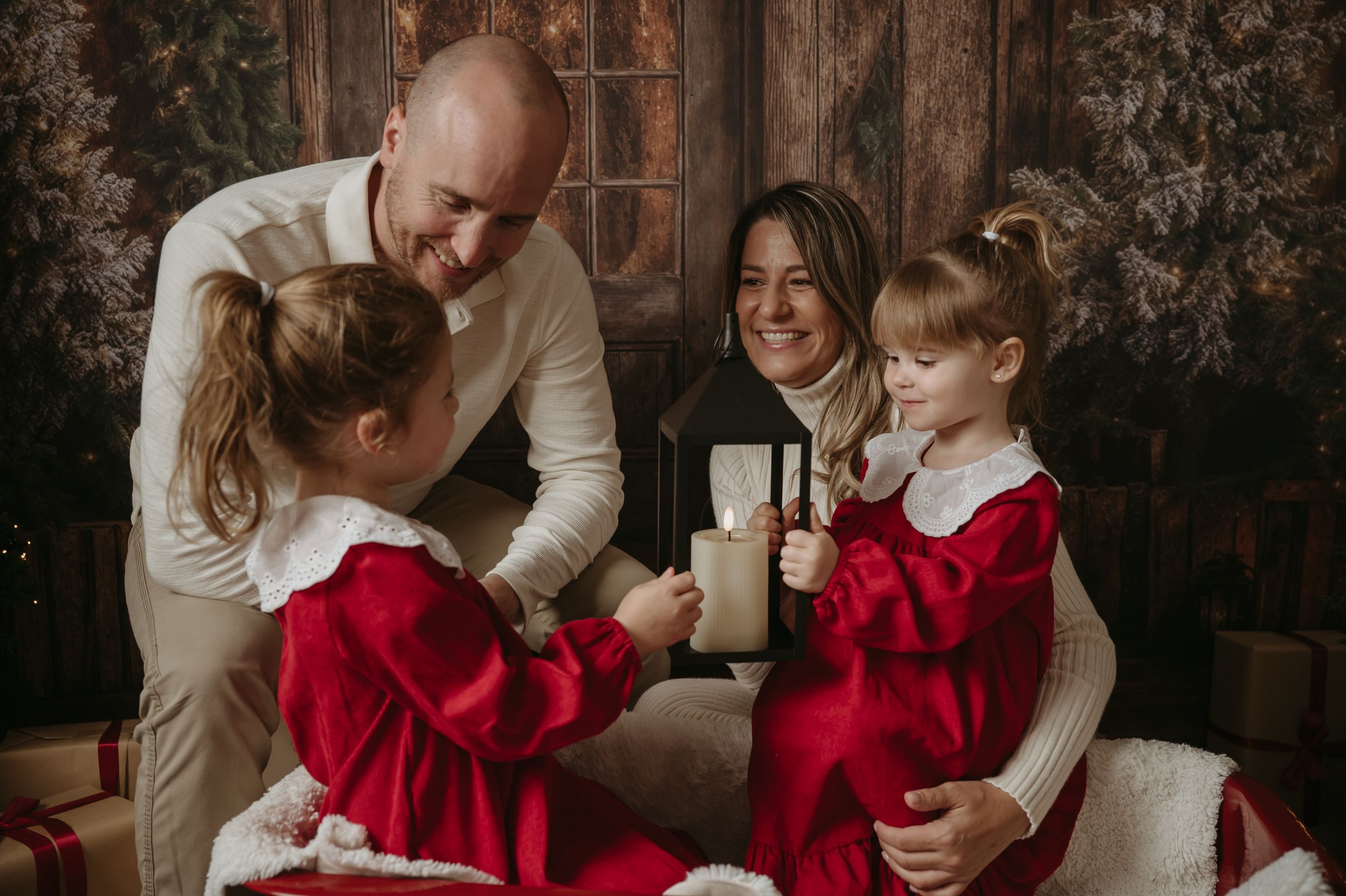 A family shares a warm moment together during a holiday photo session with children wearing festive red dresses.