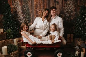 A cozy family holiday portrait session with warm lighting and rustic Christmas decor in the background.