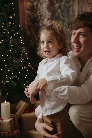 A parent and child share a joyful moment together in front of a Christmas tree with twinkling lights.