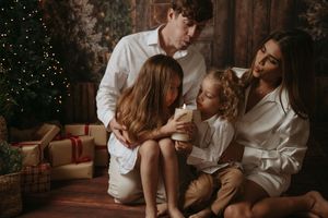 A romantic couple in white clothing shares intimate moments during a cozy indoor photoshoot.
