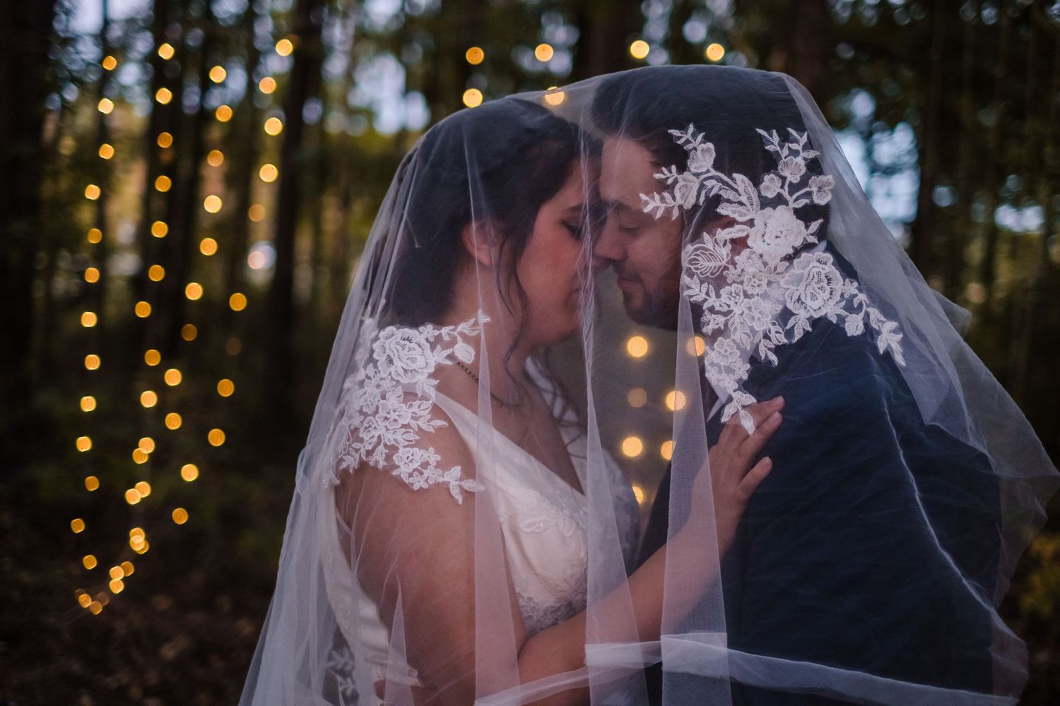 Romantic wedding couple shares intimate moments under twinkling lights during their outdoor evening celebration.