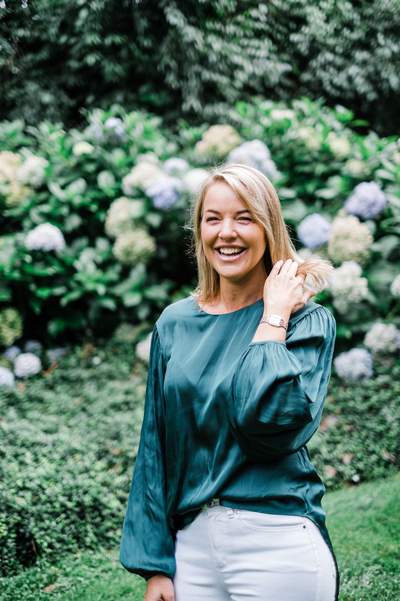 A joyful moment captured in a garden with blooming hydrangeas and greenery in the background.