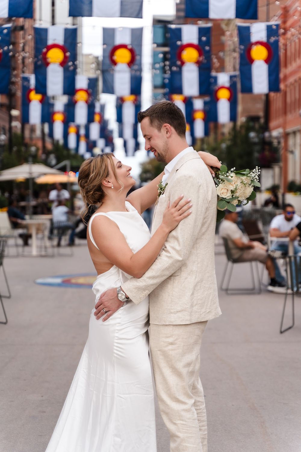 A couple in wedding attire shares a romantic dance sequence in an outdoor plaza decorated with colorful lanterns.