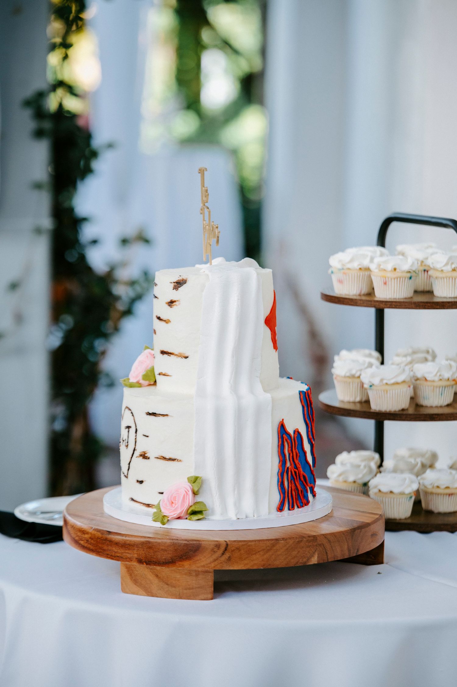 White wedding cake and cupcake display featuring birch tree design and rustic wooden stands.