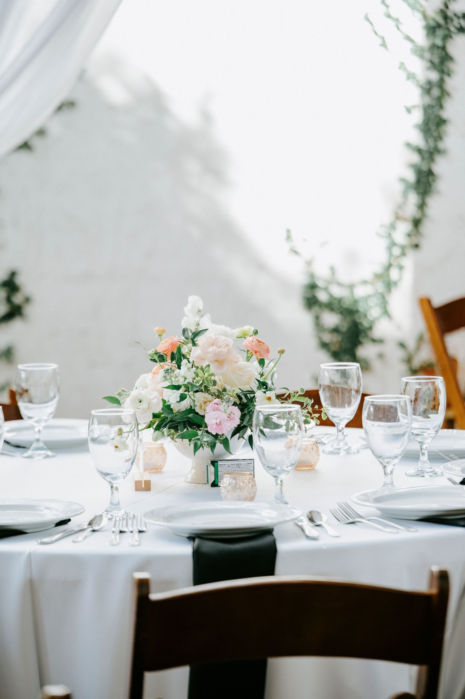 Elegant wedding reception table setting with white linens, floral centerpieces, and crystal glassware.