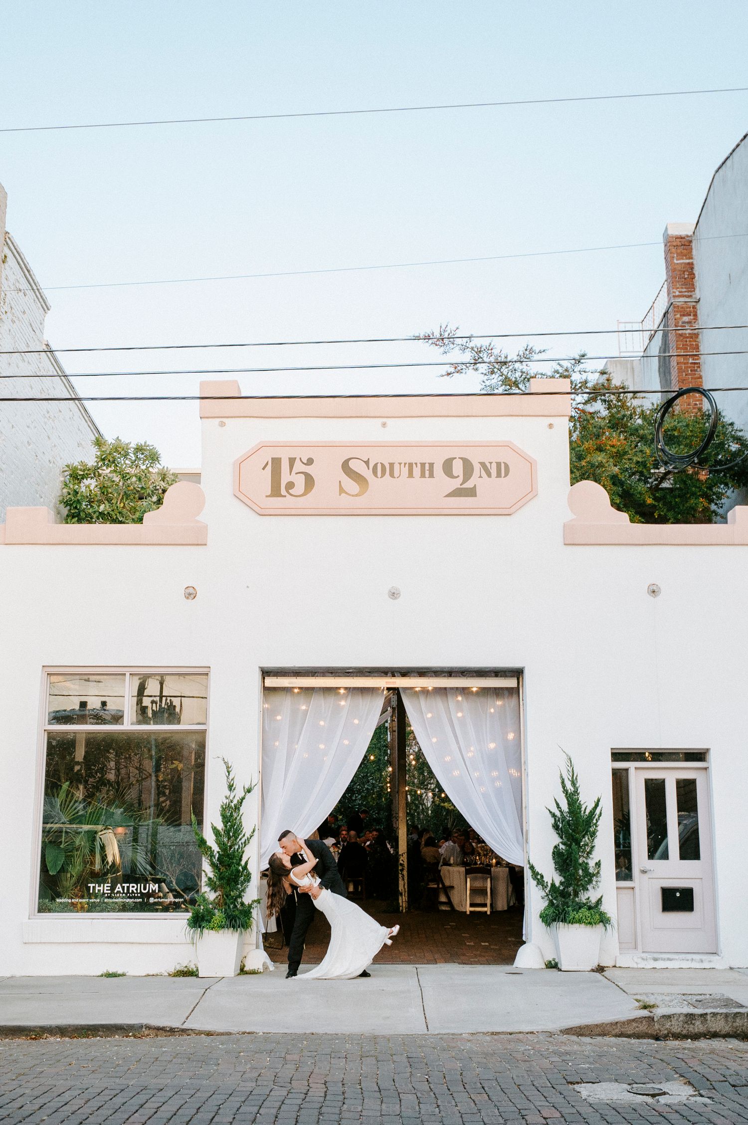 White stucco building facade with vintage signage and flowing white curtains in windows.