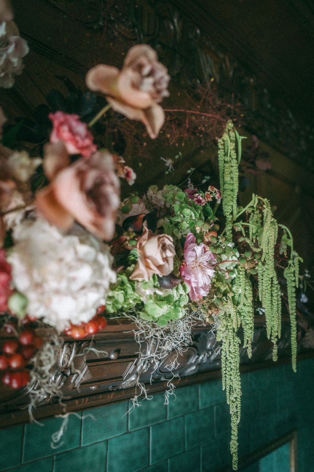 Decorative hanging floral arrangements with green foliage and pink blooms on dark background.
