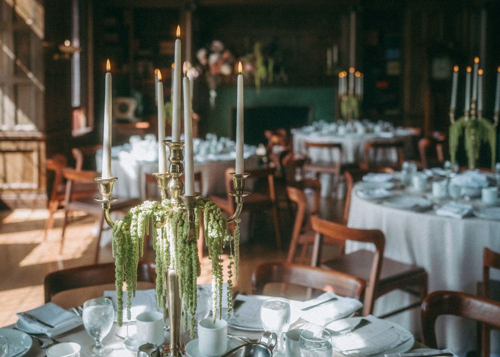 Elegant table settings with white linens and tall candlesticks in a formal dining room.