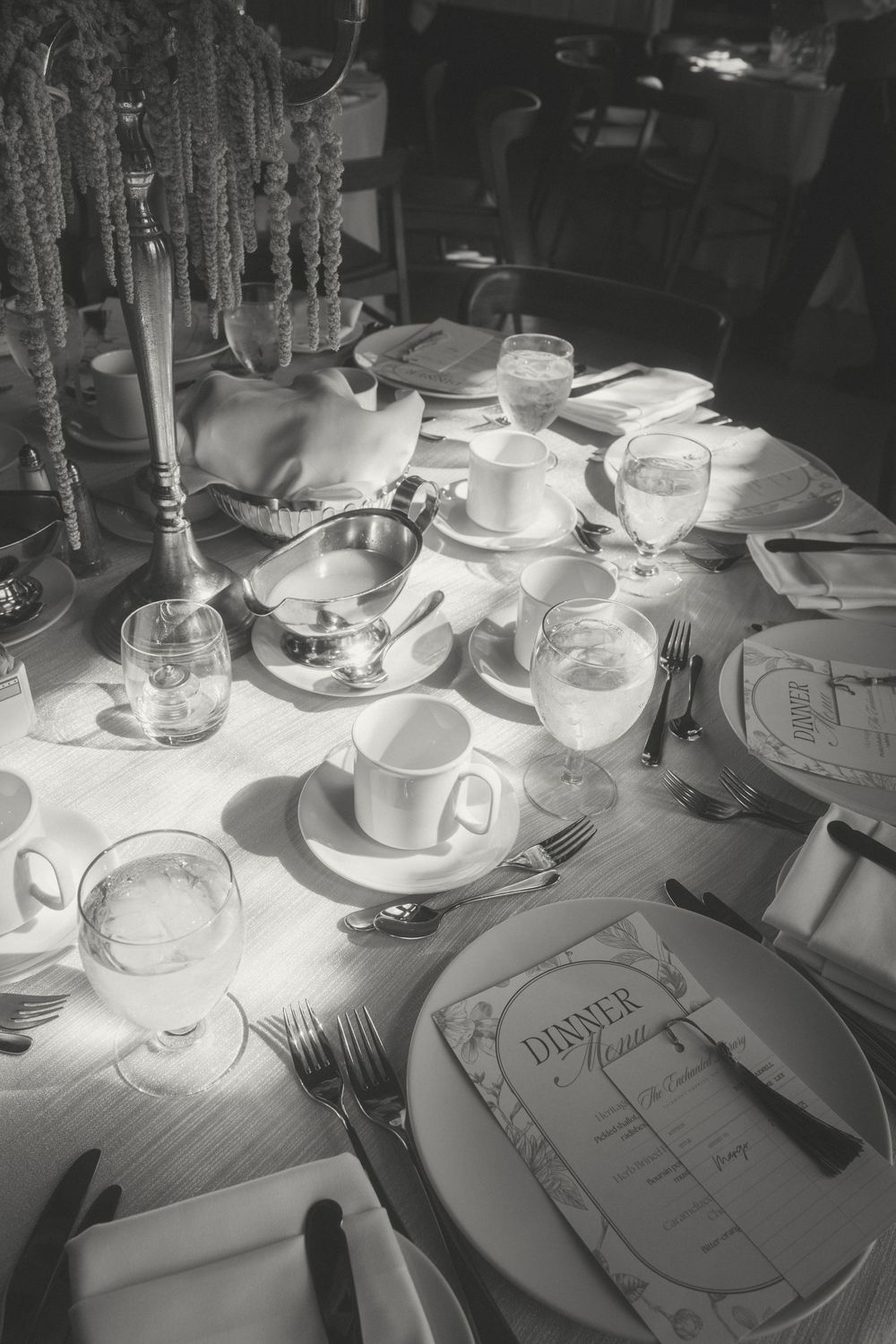 Place settings with teacups and menus arranged on a white tablecloth.