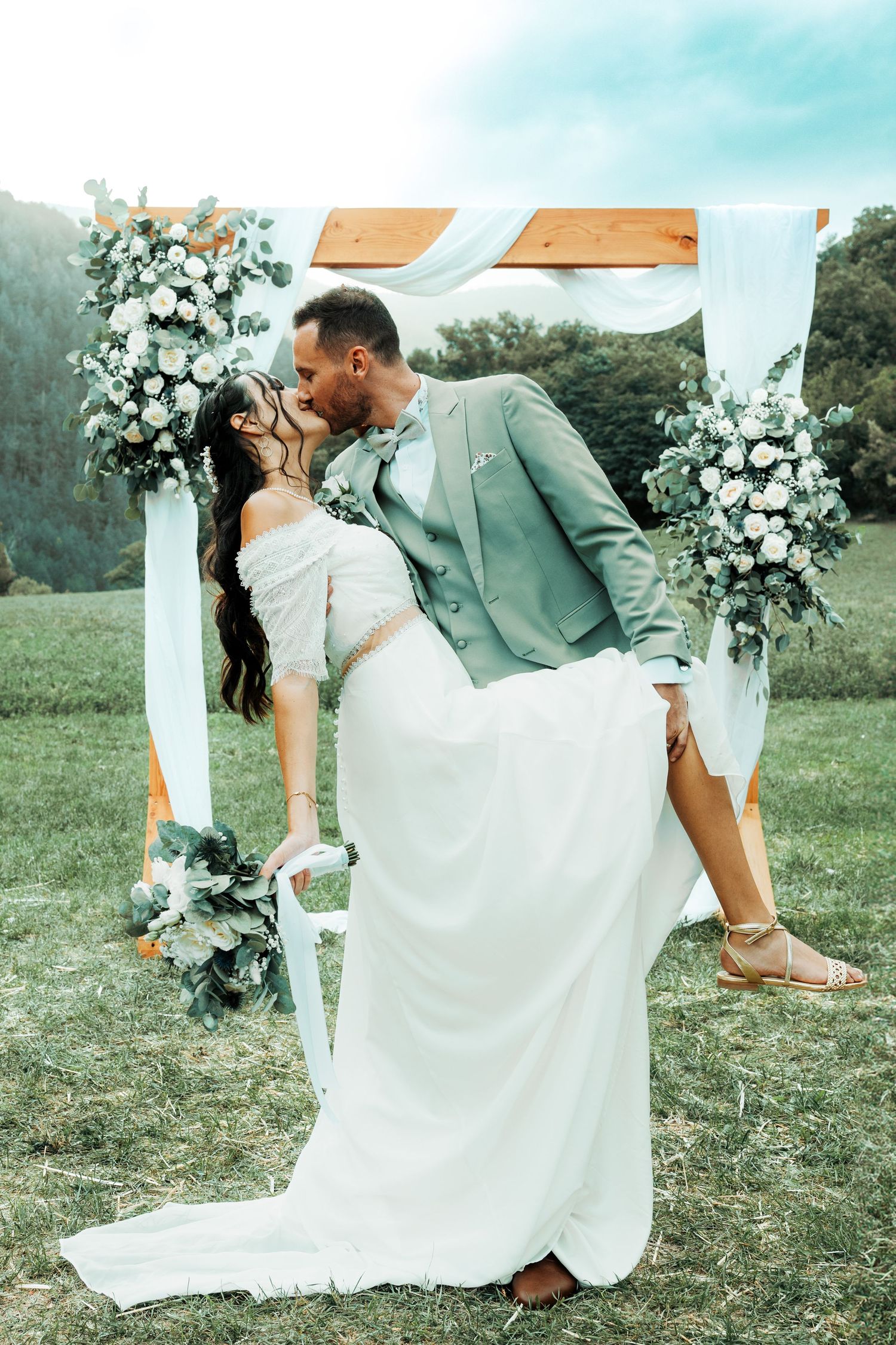 Romantic wedding dip pose in garden setting with white floral arch backdrop. Domaine des sources photographe de mariage