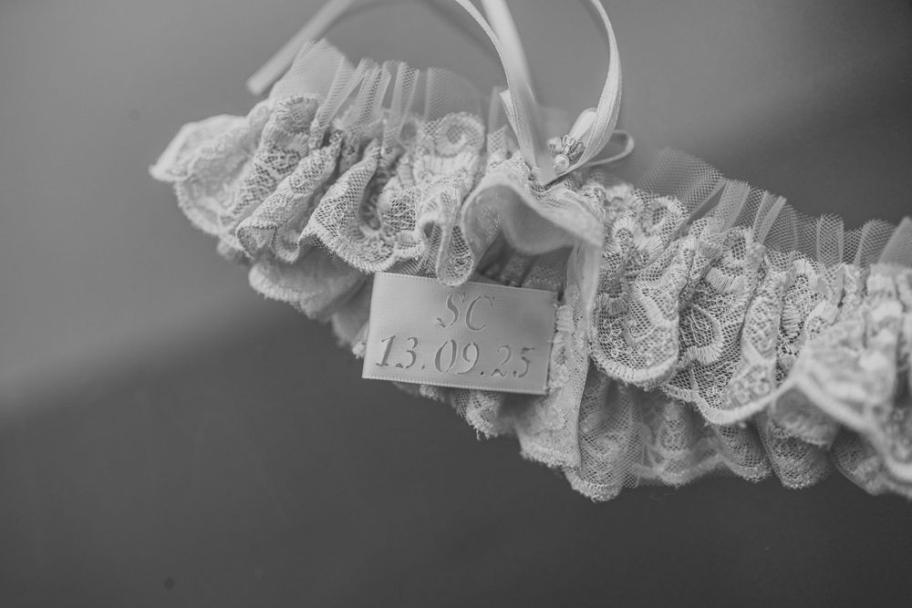 Delicate white lace garter with intricate details against a light background.
