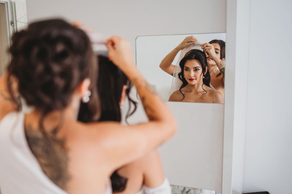 Getting ready shots of a bride in an elegant white dress with intricate lace details.