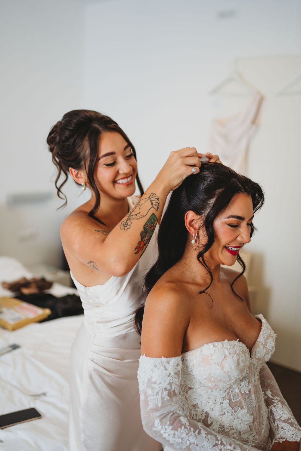 Joyful wedding preparation moment in white dresses.