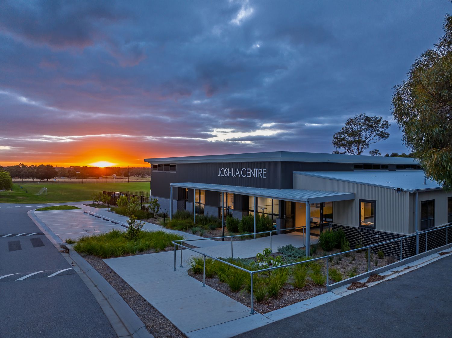 Joshua Centre modern commercial building photographed at sunset with dramatic orange and purple sky.