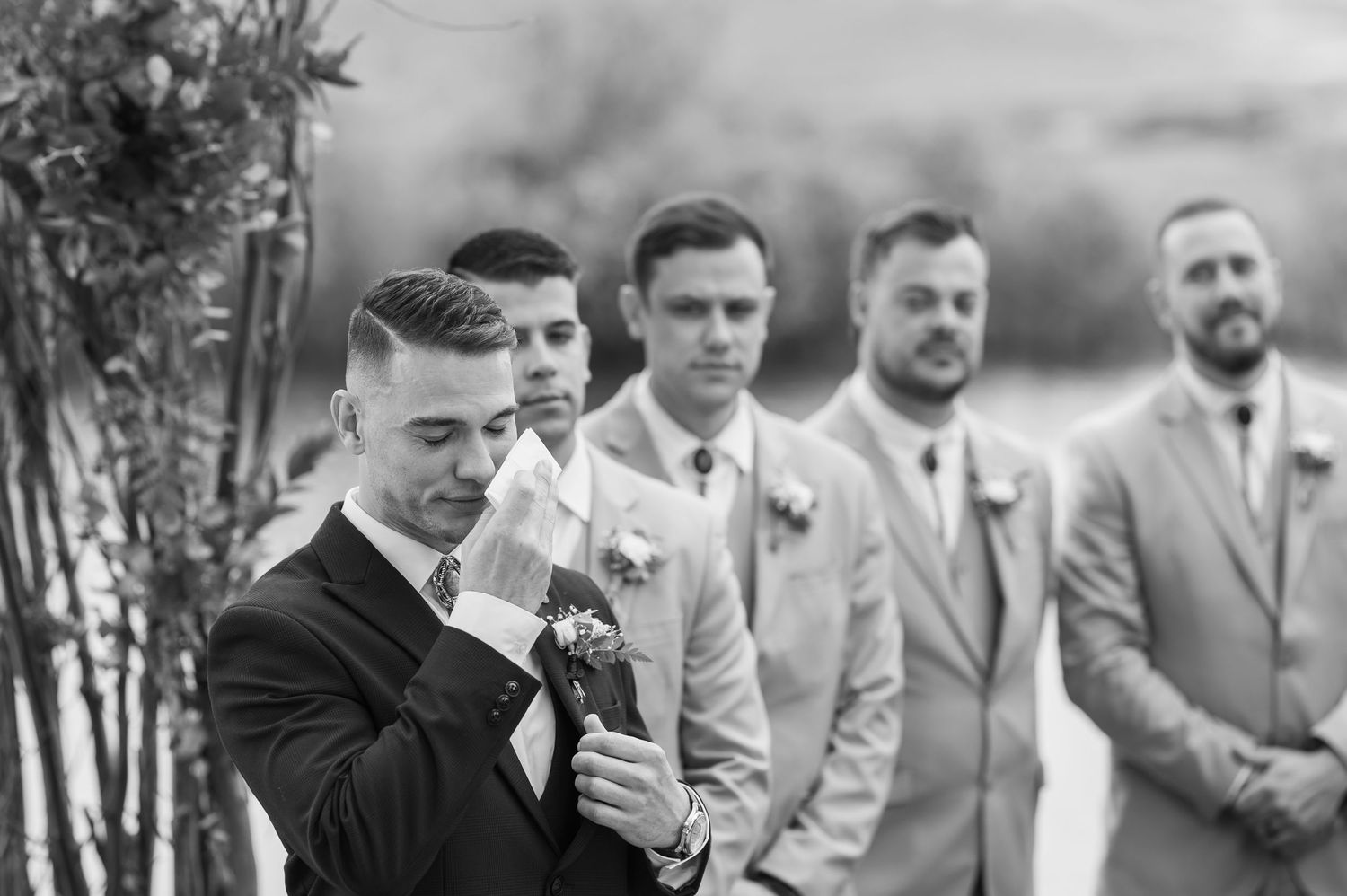 A collection of black and white wedding photos showing candid moments between people at an outdoor ceremony.