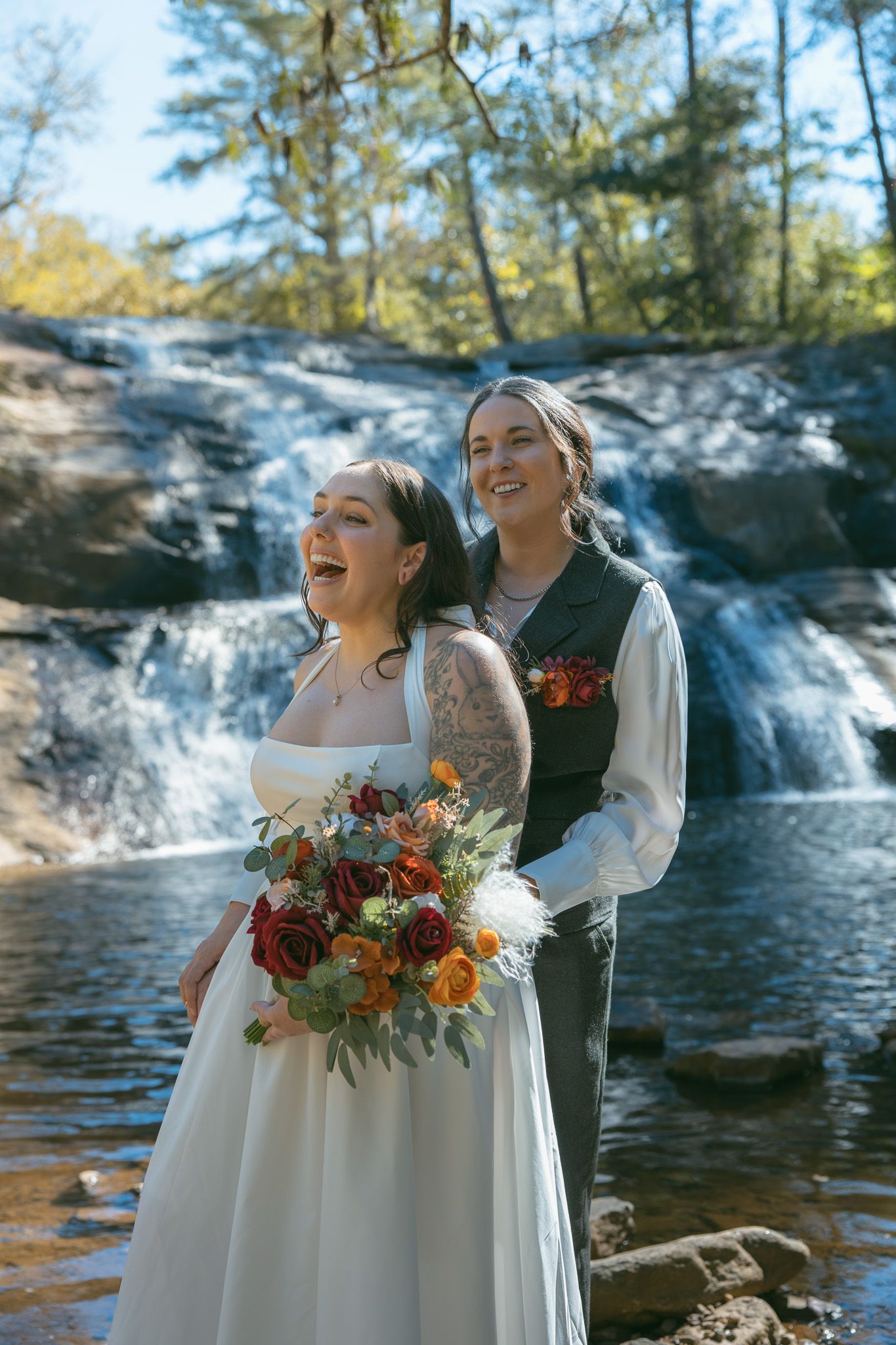lesbian couple at waterfall elopement with florals and vows asheville nc