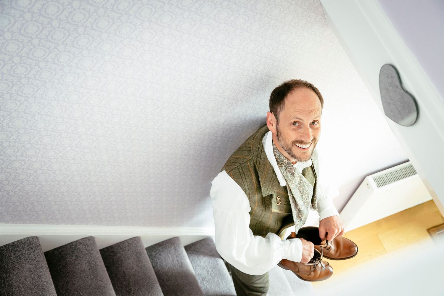 Person peeking through a hole in a white surface while holding a coffee mug.