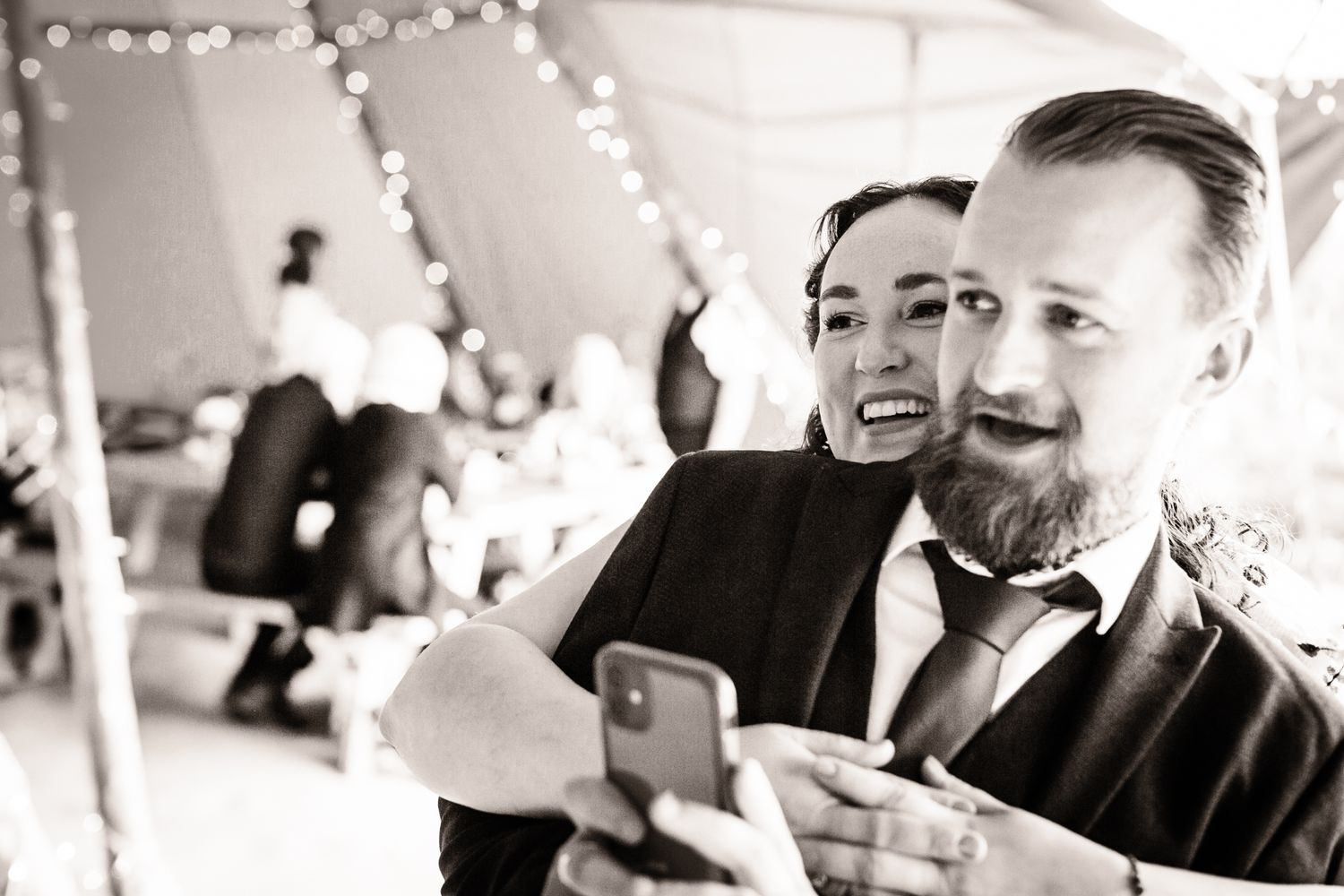 Black and white photo of wedding guests laughing and enjoying themselves during a reception celebration.