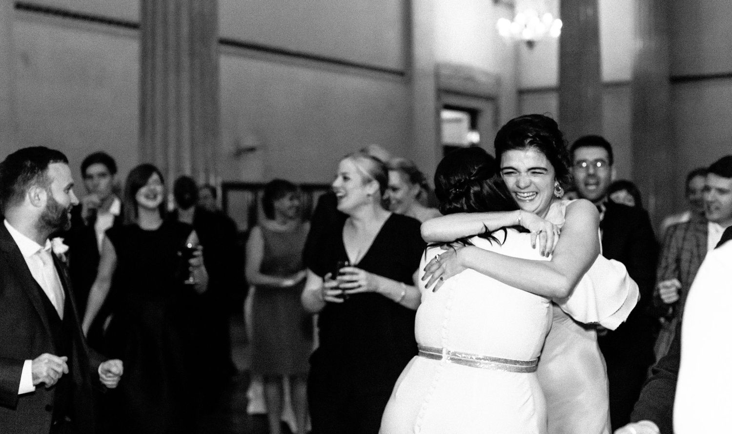 Black and white photo of couples slow dancing at a formal event while others watch from the sidelines.